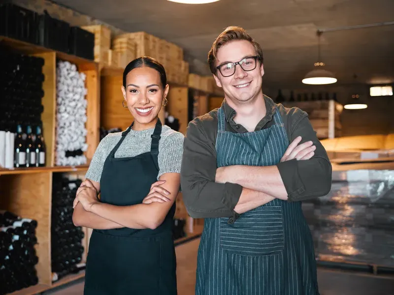 Warehouse Owners Smiling Confidently in Stockroom Environment Two smiling business owners in warehouse stockroom with arms crossed, business directory entrepreneurial spirit
